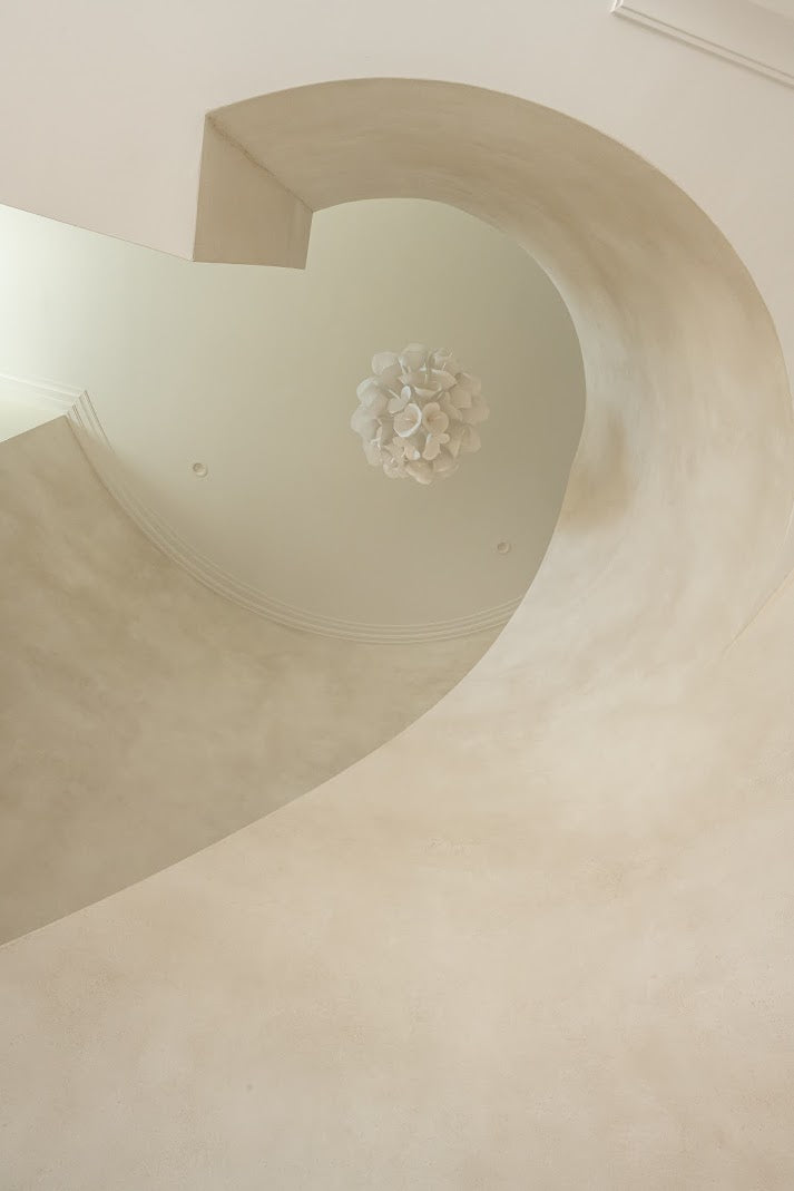 Image of a textured plaster installation on Daniel Island, SC in a two story staircase. The image is shot from the floor looking up to see the architectural detail and the movement of the plaster. 
