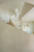 Image of a textured plaster installation on Daniel Island, SC in a two story staircase. The image is shot from the floor looking up to see the architectural detail and the movement of the plaster. 