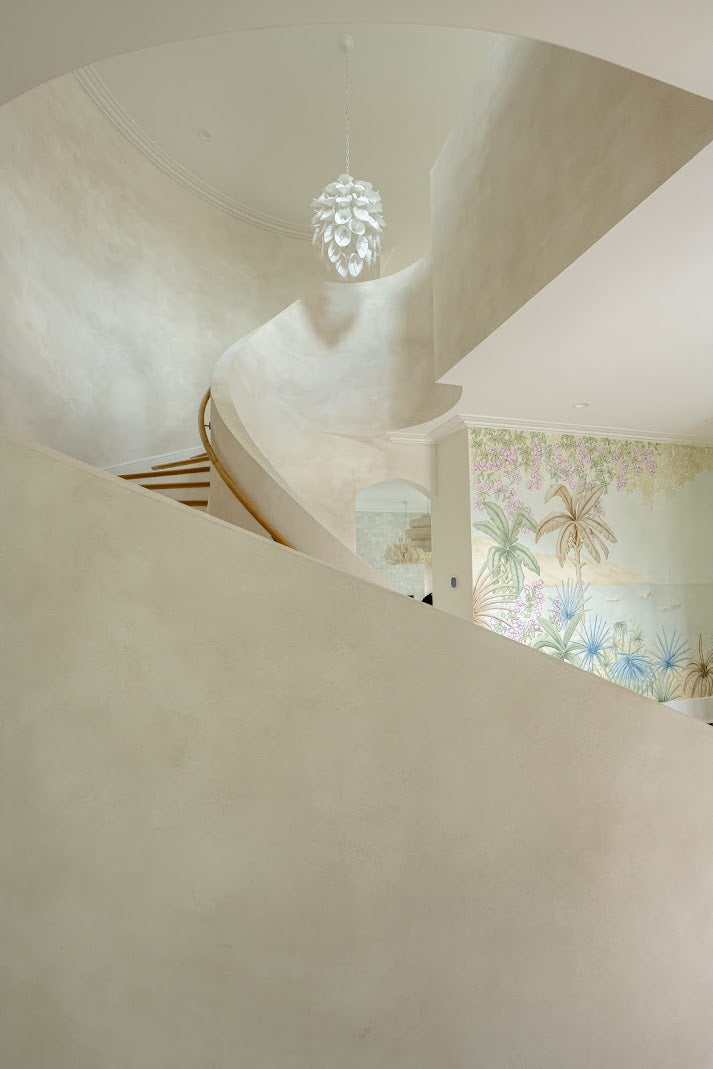 Image of a textured plaster installation on Daniel Island, SC in a two story staircase. The image is shot from the floor looking up to see the architectural detail and the movement of the plaster. 