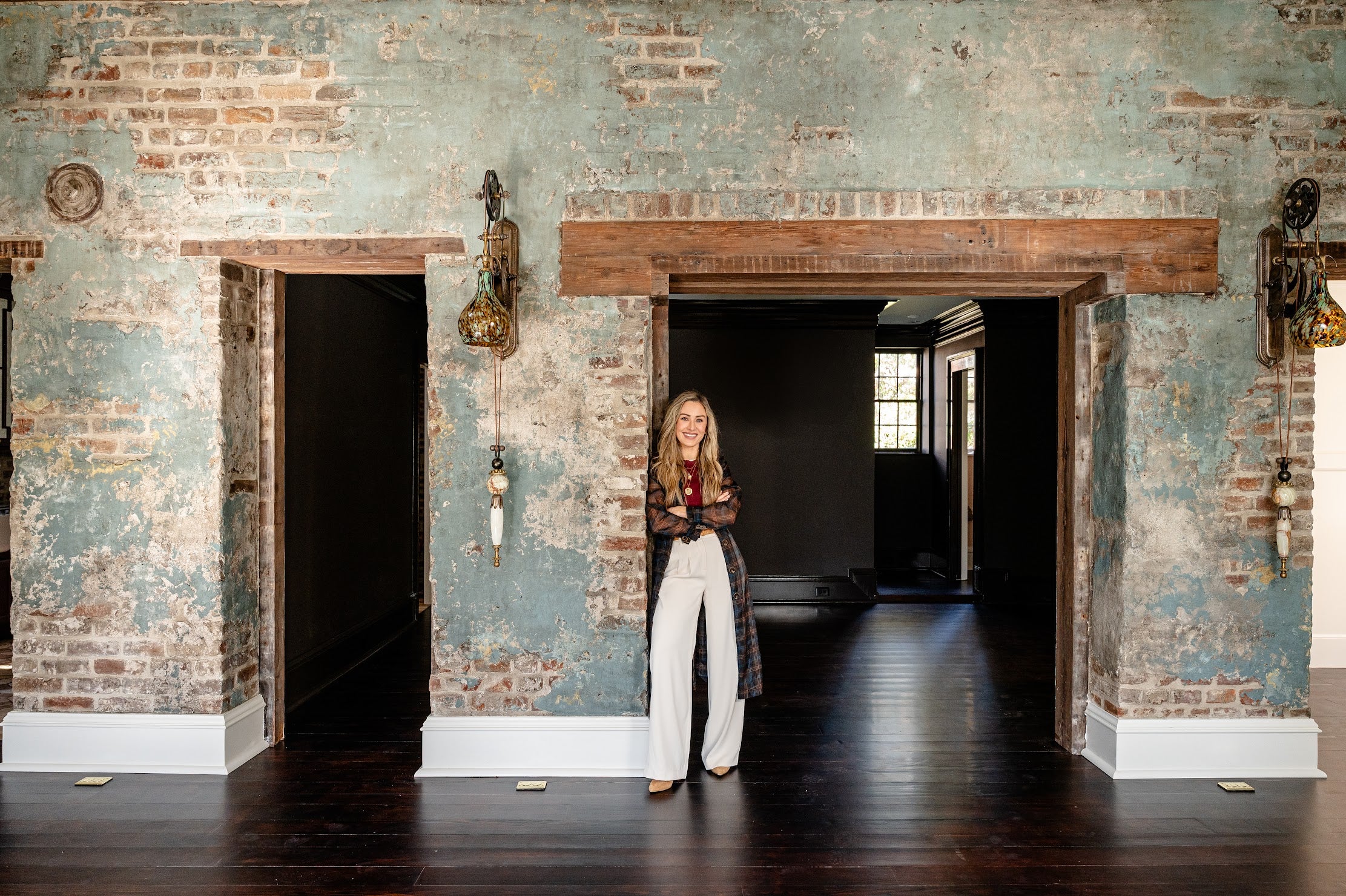 Straight-on view of historic Charleston brick wall with Emily standing in front, showing the textured plaster and glaze finish.