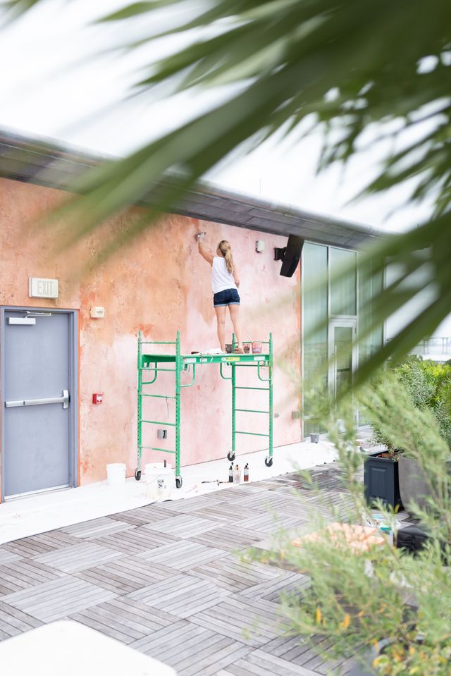 Emily Pope Harris working on a heavily textured citrus-colored plaster wall at the Citrus Club atop The Dewberry hotel in downtown Charleston.