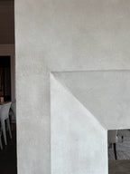 A close up image of a double-sided fireplace on Kiawah Island finished with a subtly textured plaster and a custom warm, creamy glaze created by Emily Pope Harris. The finish adds depth and softness to the space, blending natural light with gentle movement and variation across the surface.