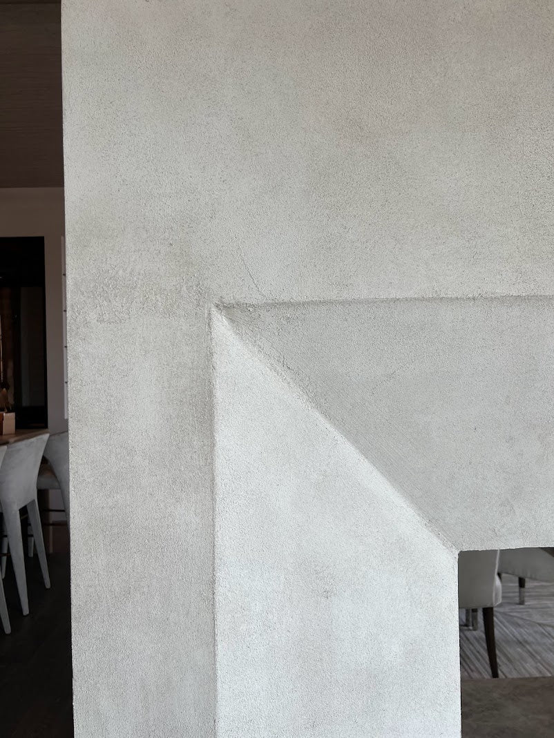A close up image of a double-sided fireplace on Kiawah Island finished with a subtly textured plaster and a custom warm, creamy glaze created by Emily Pope Harris. The finish adds depth and softness to the space, blending natural light with gentle movement and variation across the surface.