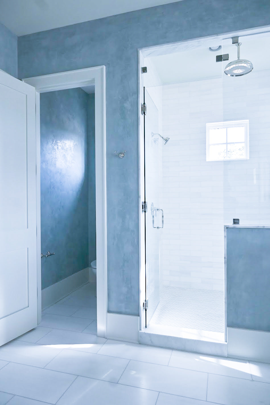 Light blue venetian plaster in Yarmouth blue in a primary bathroom on the walls and ceiling in the water closets. 