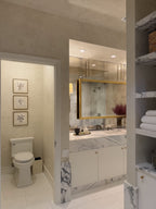 Two-tone cream Venetian plaster installation covering walls and ceiling in the primary bathroom and water closet at the Palm Beach Kips Bay Designer Show House, hand-applied and polished by Emily Pope Harris.