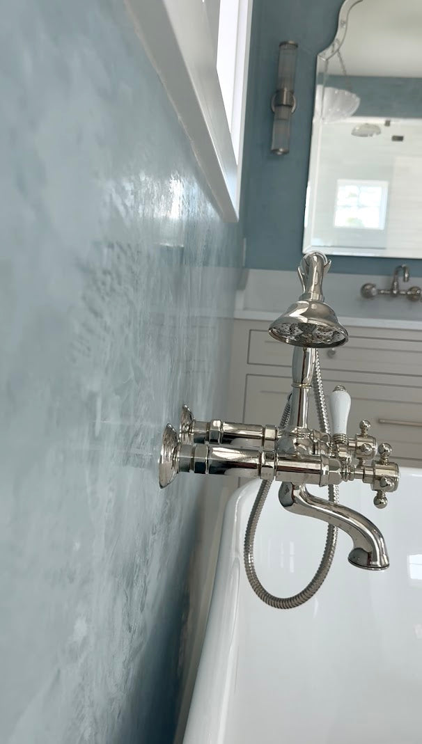 Close-up side view of light blue Venetian plaster in a Ravenel, SC master bathroom, showing burnish and polish finish reflecting natural light, by Emily Pope Harris for Jackson Built Custom Homes.