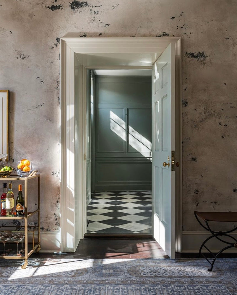 Custom charcoal-gray plaster walls with rich texture and layered finishes by Emily Pope Harris in the music room of Darius Rucker’s house, designed by Betsy Berry, highlighting dimensional surfaces, color variation, and architectural patina inspired by Charleston and Europe.