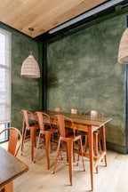 Wide view of a custom textured plaster wall with layered olive-green glaze, showing movement, depth, and dimension in a commercial space at The Refinery in downtown Charleston by Emily Pope Harris.