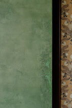 Detailed view of textured plaster wall with custom olive-green glaze beside bold patterned wallpaper and cabinetry at The Refinery in Charleston, SC by Emily Pope Harris.