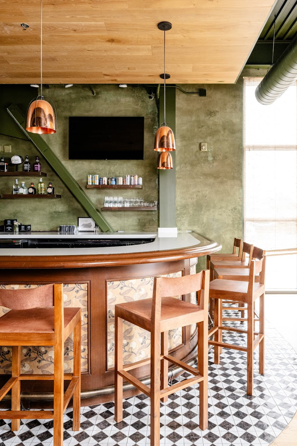 Close-up of the bar and surrounding textured plaster wall with layered olive-green glaze at The Refinery, a commercial plaster installation in Charleston, SC by Emily Pope Harris.
